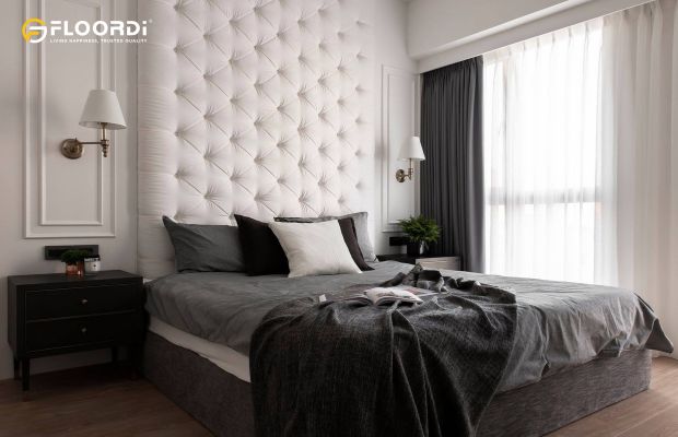 A floor-to-ceiling upholstered headboard featuring classic diamond tufting creates a luxurious, inviting backdrop